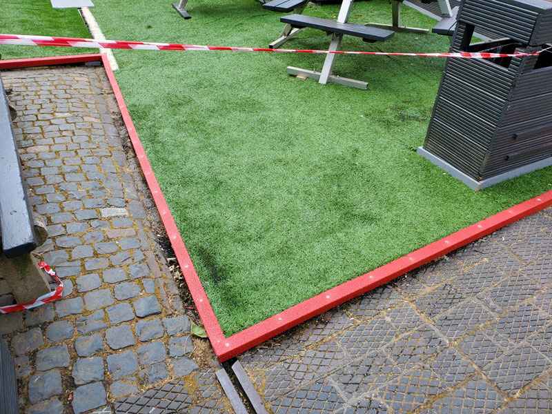 Red GRP nosing used as edging on artificial grass