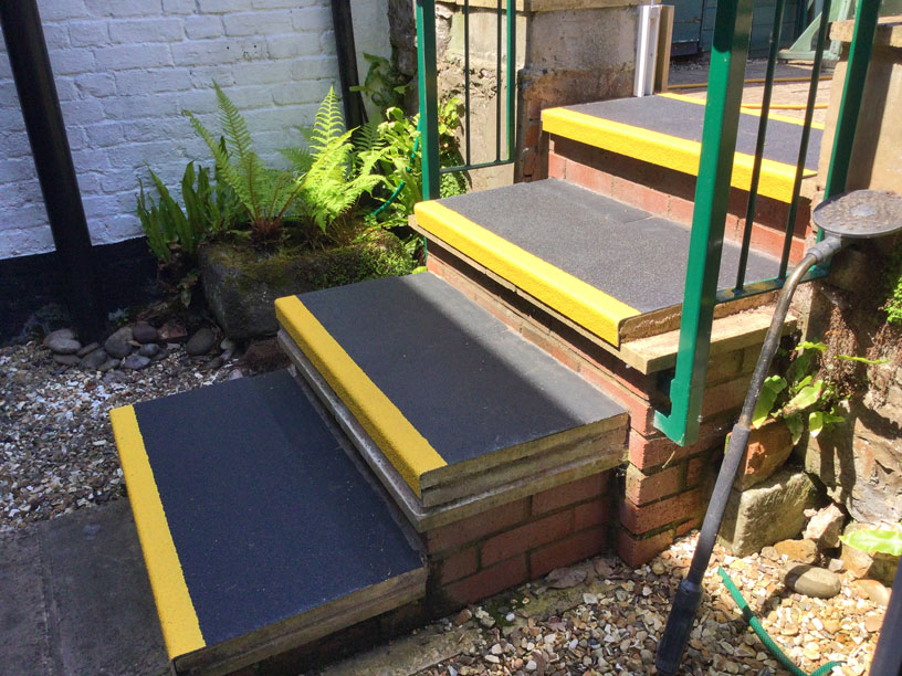 black and yellow non-slip stair treads on brick garden steps