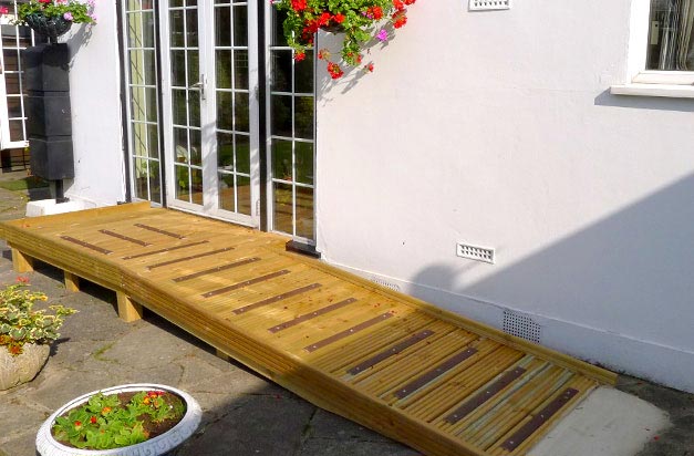 Wooden ramp access platform with non-slip decking strip areas.